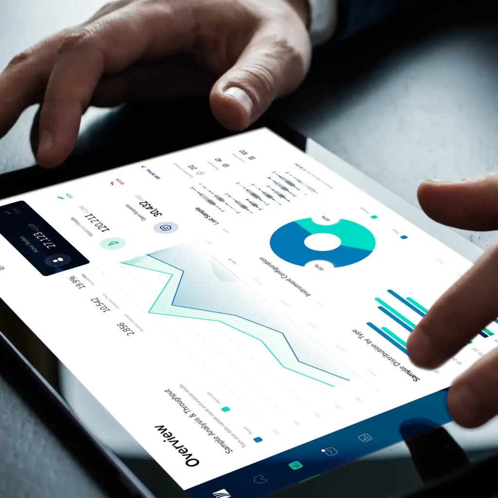 A person uses a tablet displaying data visualizations, including a line graph, bar chart, and pie chart, representing business analytics and biostatistics on a digital dashboard.