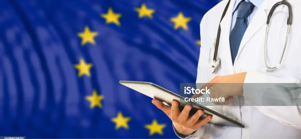 Ein Arzt in einem weißen Kittel mit einem Stethoskop bedient ein Tablet, während er vor der Flagge der Europäischen Union steht, und unterstreicht damit die Bedeutung der Einhaltung der IVDR im modernen Gesundheitswesen.